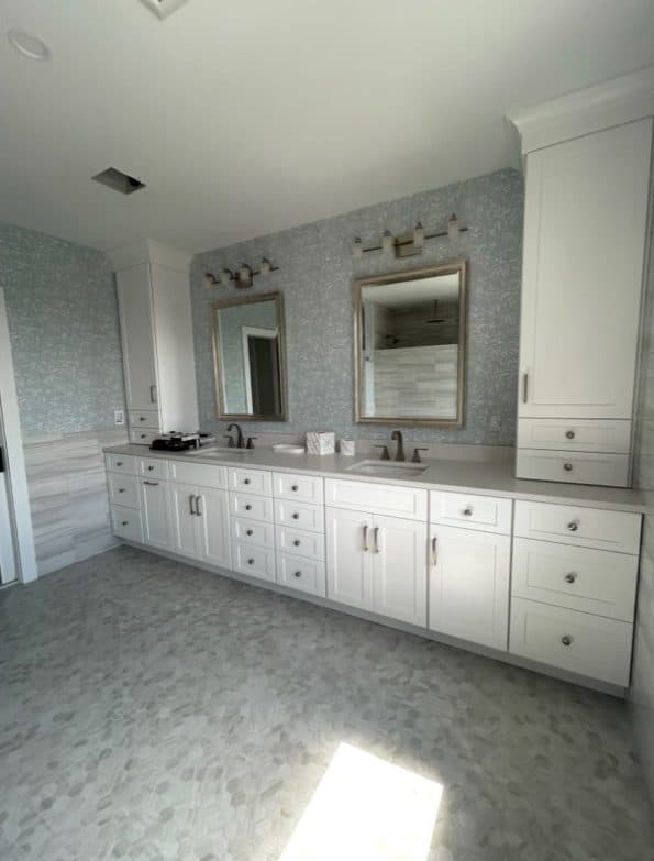 Bathroom vanity room with pale cabinetry, long counter, and patterned window treatment.