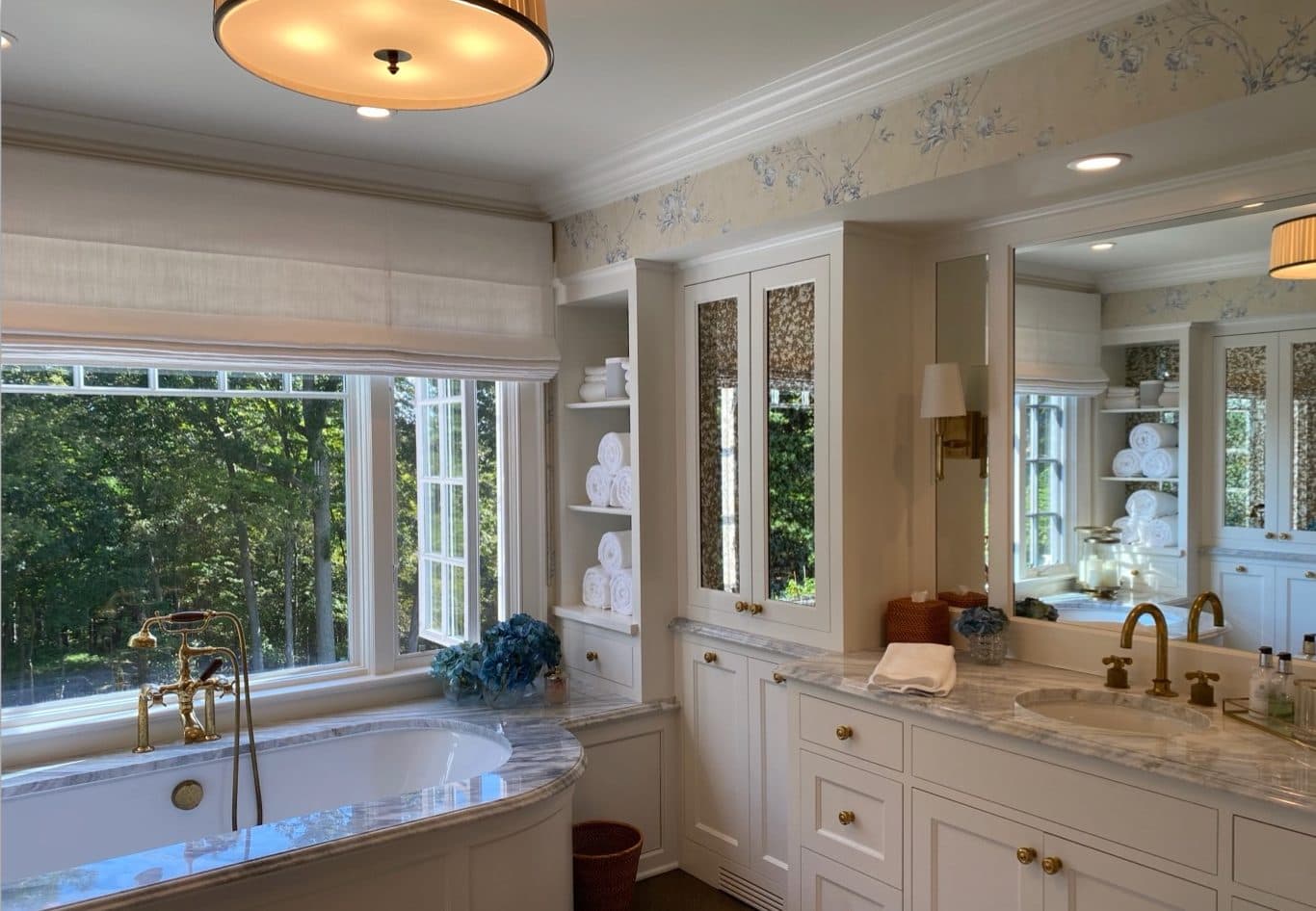 Primary bathroom with freestanding tub, double vanity, mirrors, and large window.