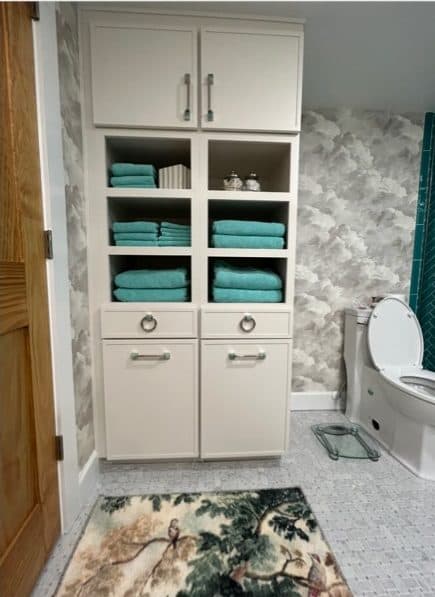 Bathroom storage cabinet with open cubbies, drawers, and woven hamper baskets.
