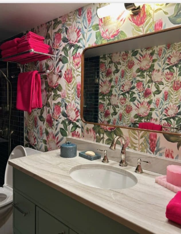 Bathroom double vanity with floral wallcovering, green cabinetry, and pink accents.