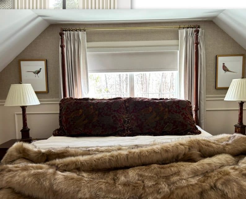 Farmhouse bedroom with layered bedding, lamps, and striped drapery.