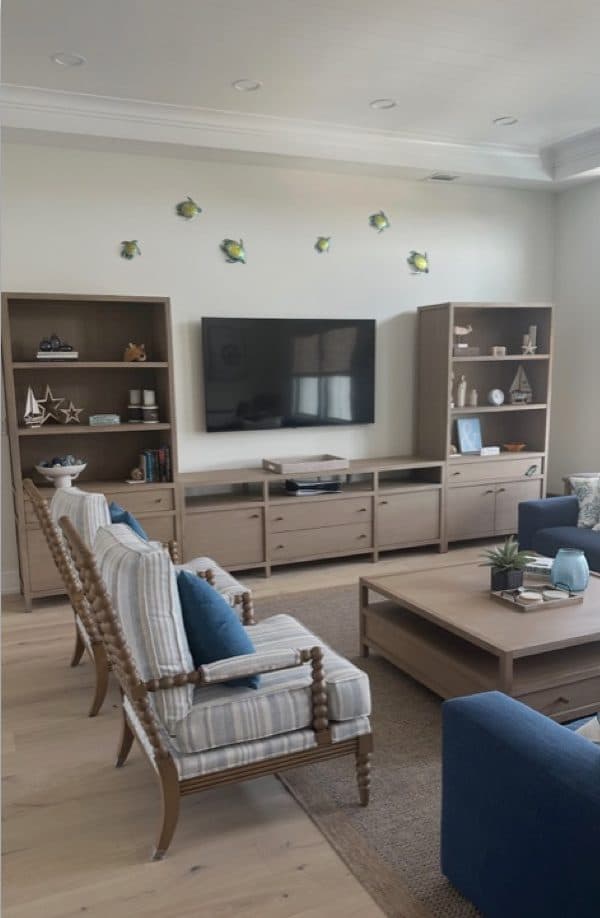 Long Beach Island sitting room with pale chairs, built-ins, and a wall-mounted television.