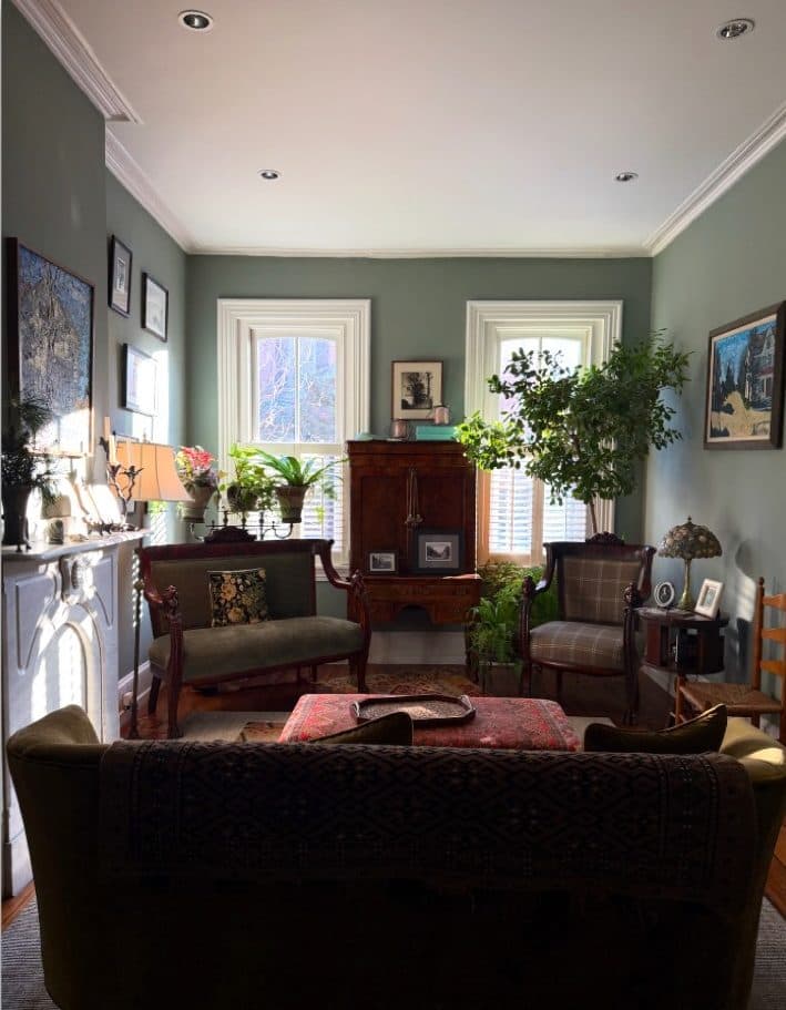 Philadelphia brownstone living room with vintage seating, dark wood furniture, and gallery wall.