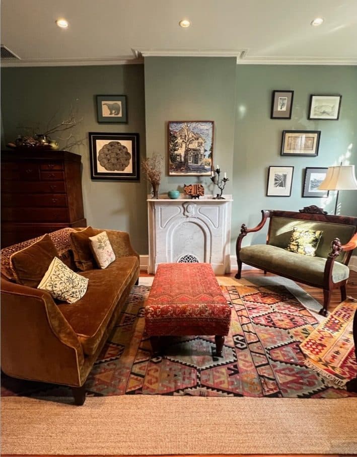 Layered Philadelphia brownstone sitting area with patterned rug, ottoman, and framed art.