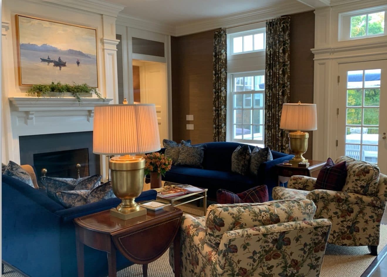 Traditional Connecticut living room with blue seating, patterned chairs, layered lamps, and fireplace artwork.