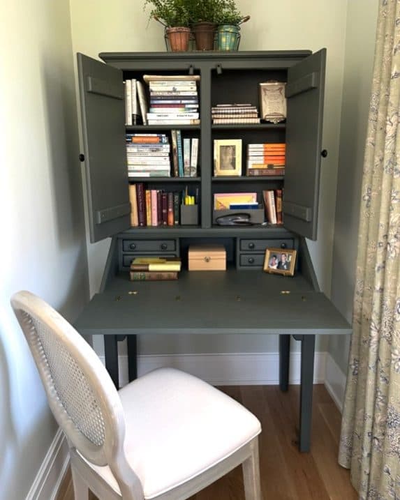 Yardley work nook with a dark desk, bookcase, and upholstered chair.